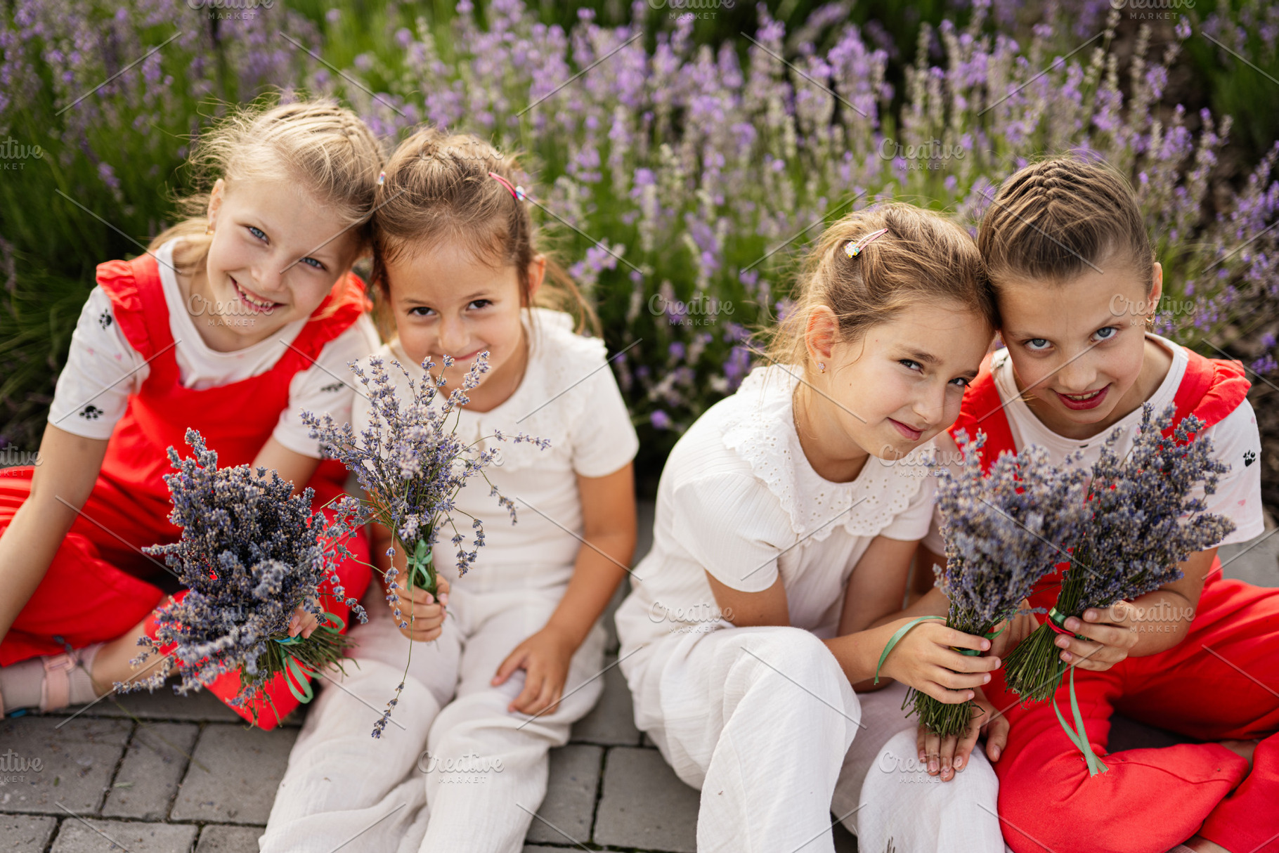 Group of happy children holding lavender bouquets outdoors in a sunny garden, a Photo by AS photostudio