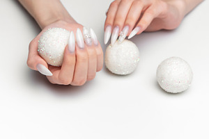 Woman hands holding sparkling christmas ornaments with long nail, a Photo by Olena Rudo