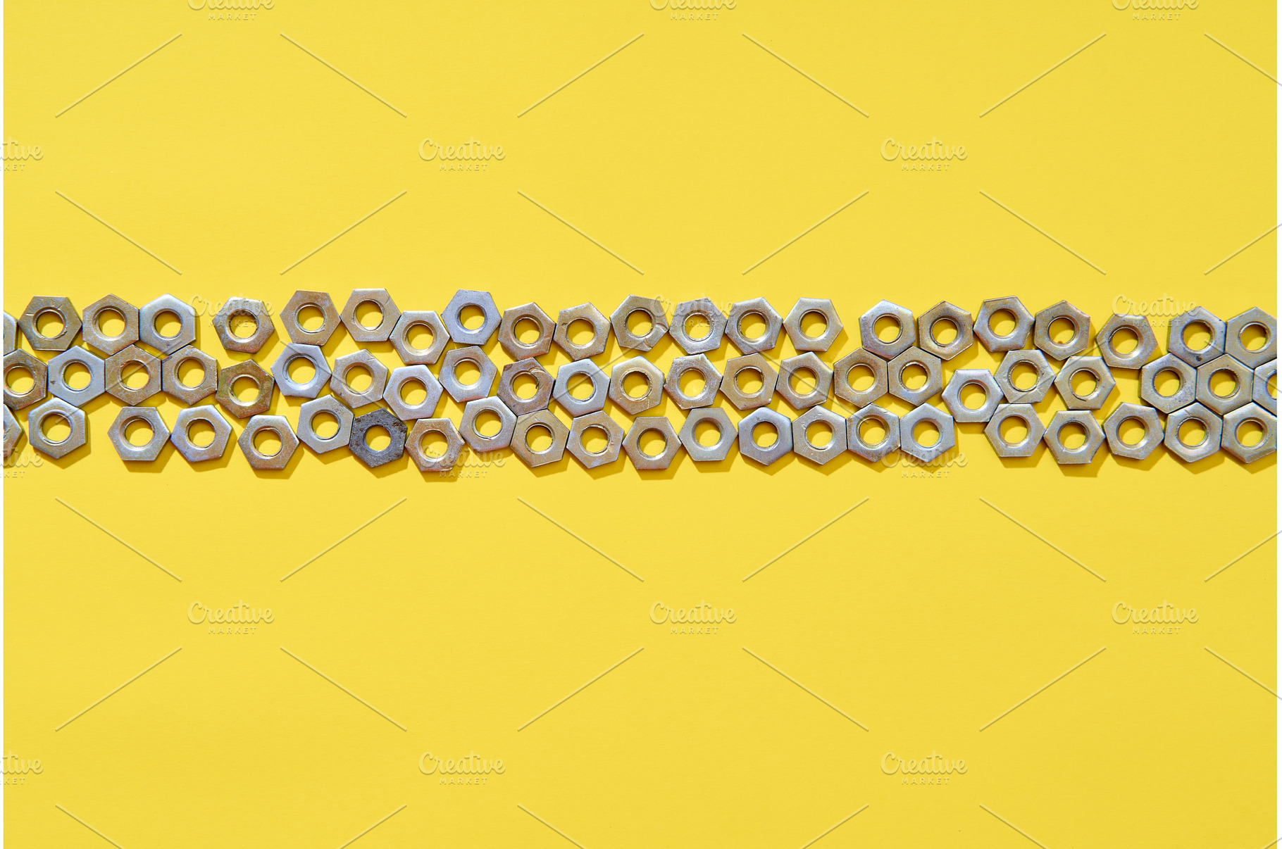 Horizontal metal nuts line on yellow, an Industrial Photo by Gladkov photography