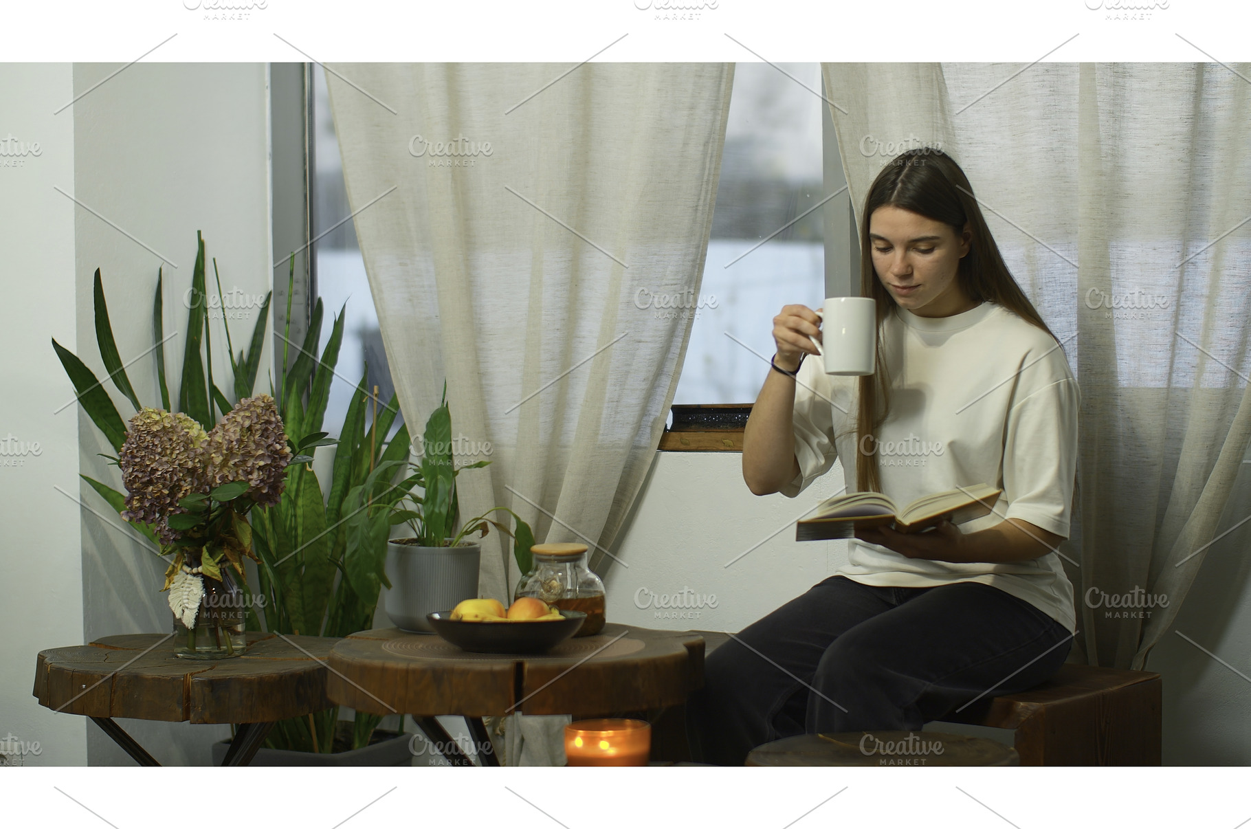Young woman is reading book with tea, a Person Photo by Media Whale Stock