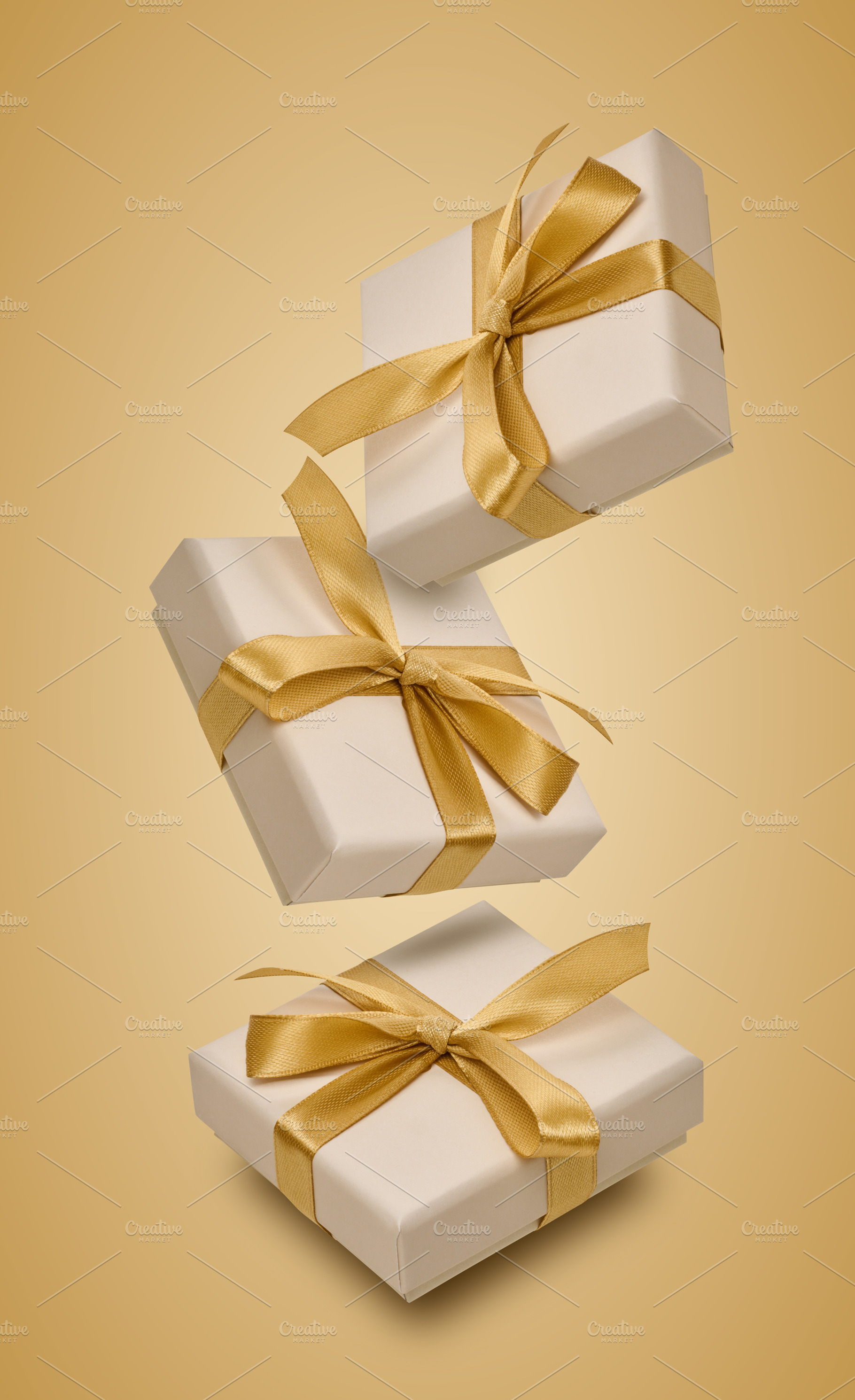 Floating beige gift boxes with gold satin ribbons and bows., a Holiday Photo by ndanko