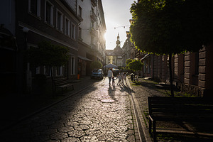 Family walking through a quiet city street at sunset with charming architecture, a Person Photo by AS photostudio