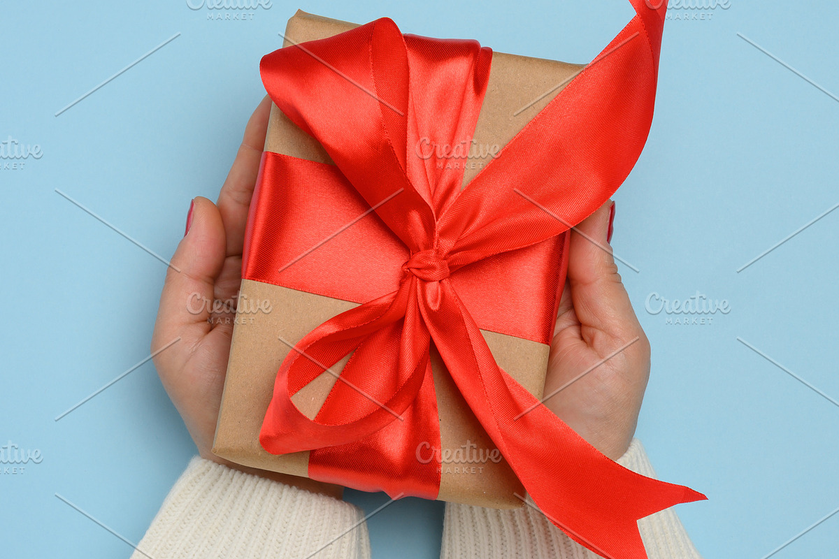 A woman's hands in a white knitted sweater hold a square gift bo, a Holiday Photo by ndanko (Photo 1 of 3)