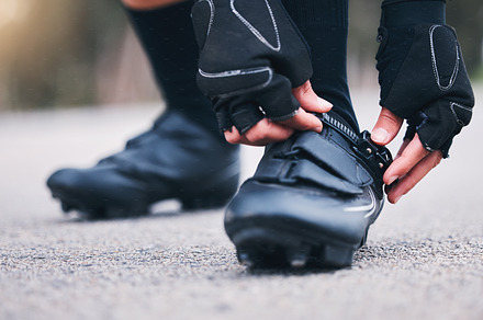 Fitness, shoes and closeup with woman in road for running, workout and sports challenge. Cardio, exercise and race with female runner fix sneakers in outdoors for training, strong and performance, a Photo by Peopleimages.com