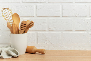 Kitchen utensils resting on wooden countertop by white brick wal, a Food & Drink Photo by Olena Rudo