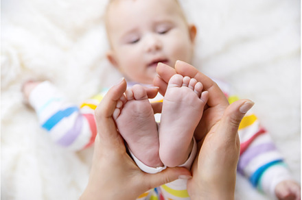 The mother holds the legs of her, a Person Photo by yanadjana
