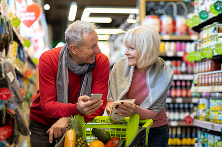 Positive elderly husband and wife shopping together, using smartphone, a Person Photo by Prostock-Studio