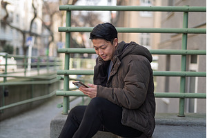 Young Asian man sitting on street, a Person Photo by HalfPoint