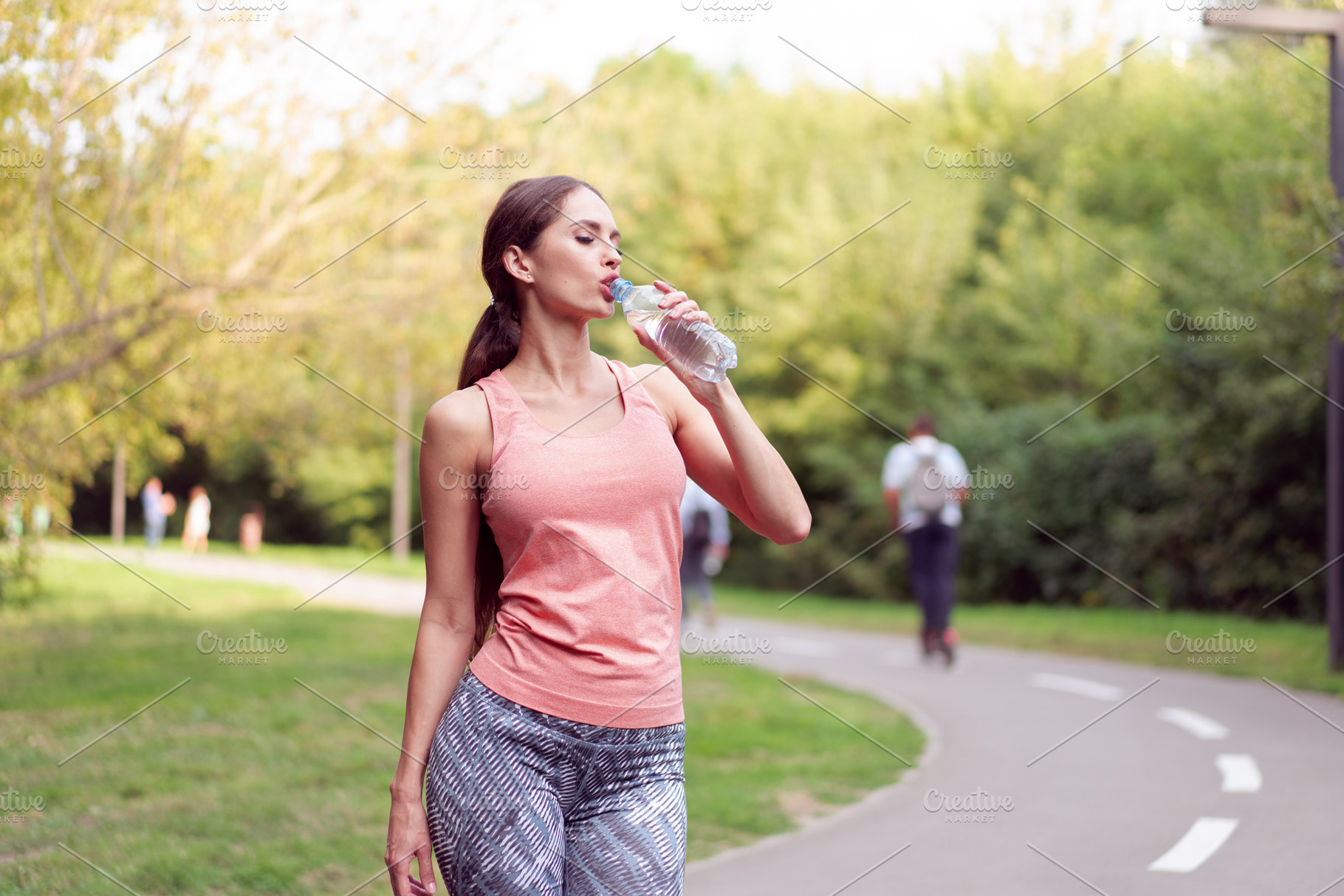 Athletic woman standing running track in summer park drink water after running, a Person Photo by andreonegin market