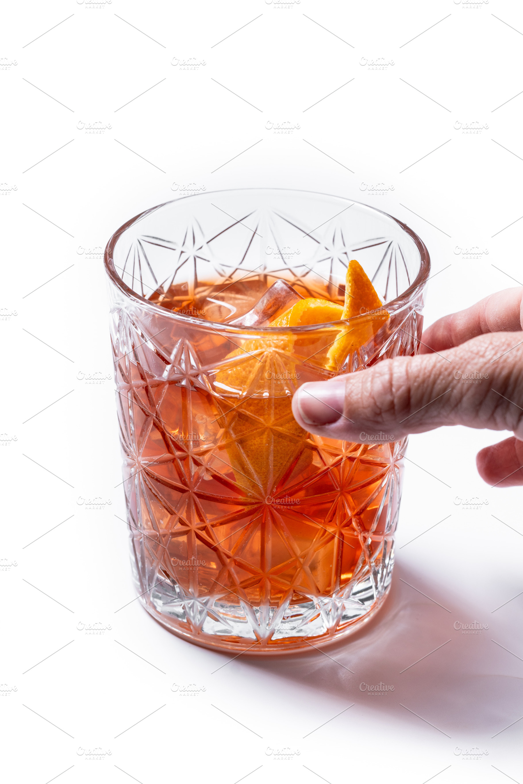 Hand reaching for an Old Fashioned cocktail in crystal glass, a Photo by etorres69