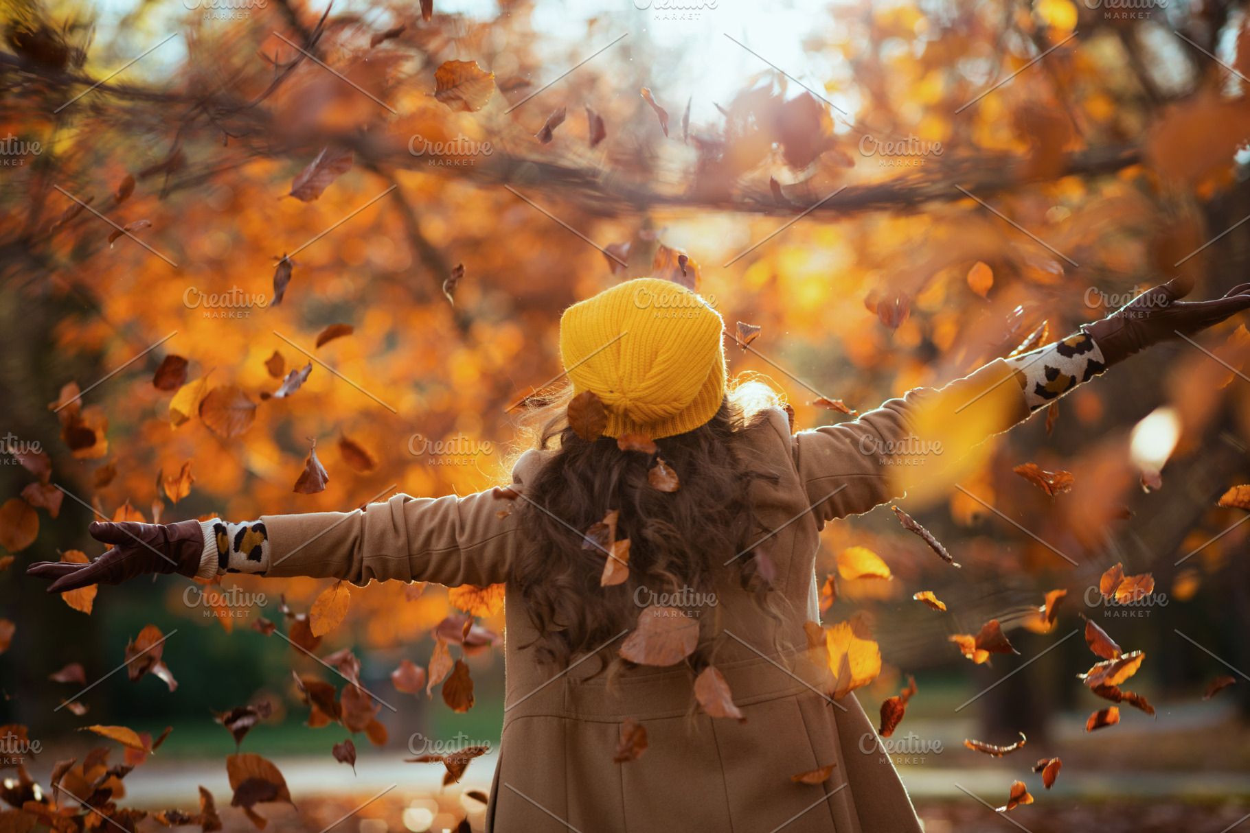 Seen from behind woman in beige coat and orange hat rejoicing, a Person Photo by Alliance Images