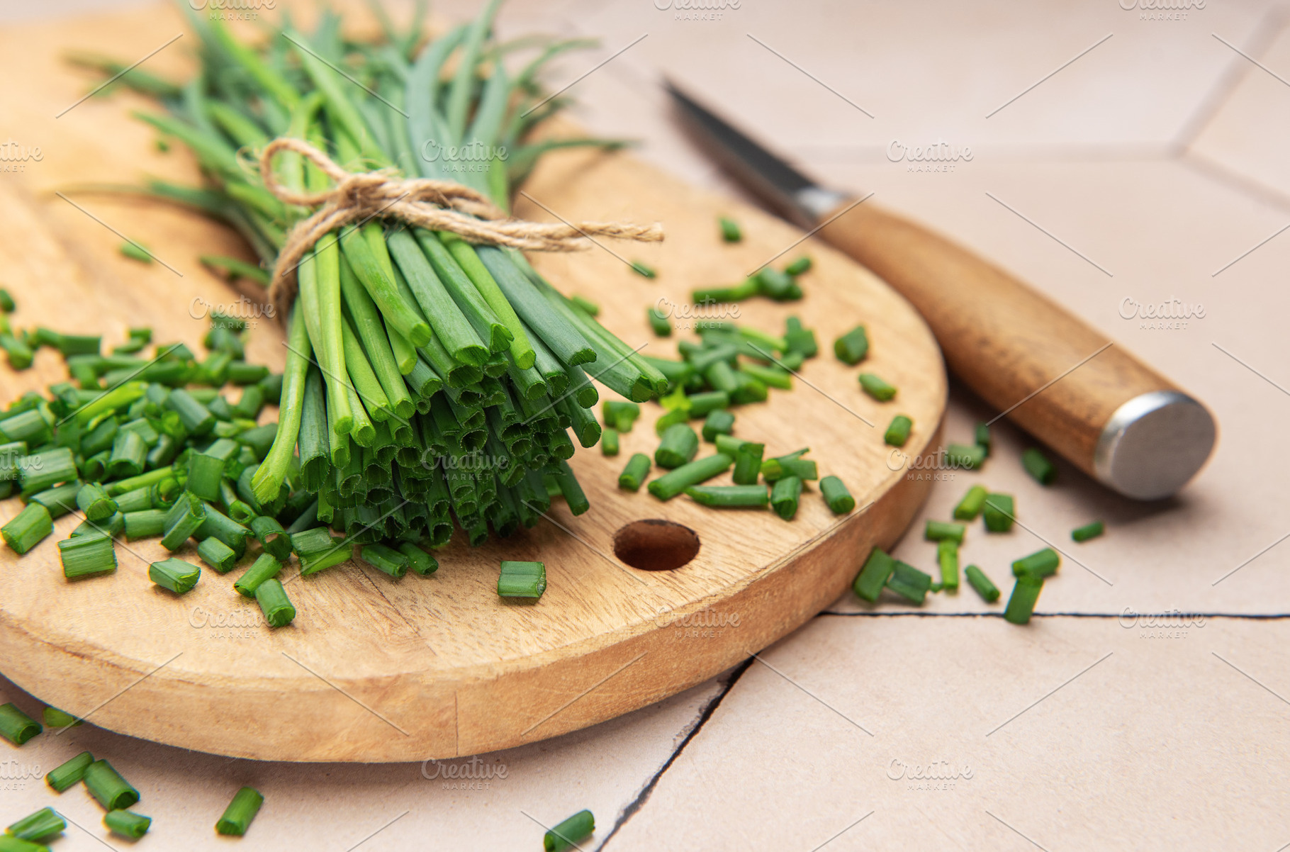 Freshly cut chives on wooden cutting board with knife, a Photo by Olena Rudo