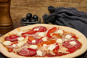 Pizza with salami, ham and mozzarella cheese on parchment, a Food & Drink Photo by ndanko