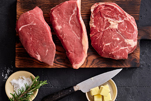 Raw rib-eye, roast beef, flank and rump steak arranged on a wooden cutting boar, a Food & Drink Photo by Asya Nurullina