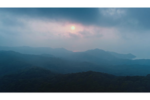 Sun setting behind misty mountains, a Nature Photo by Goinyk