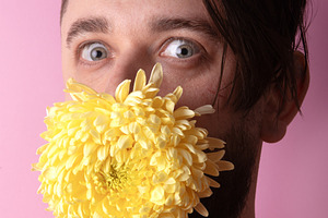 Young man with large yellow chrysanthemum covering mouth, standi, a Person Photo by Ales Munt