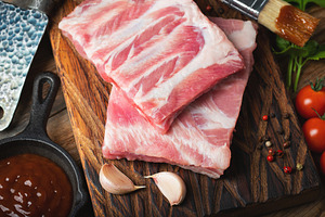 Raw pork ribs with spices, salt and rosemary on dark wooden background, a Food & Drink Photo by Budarinphoto