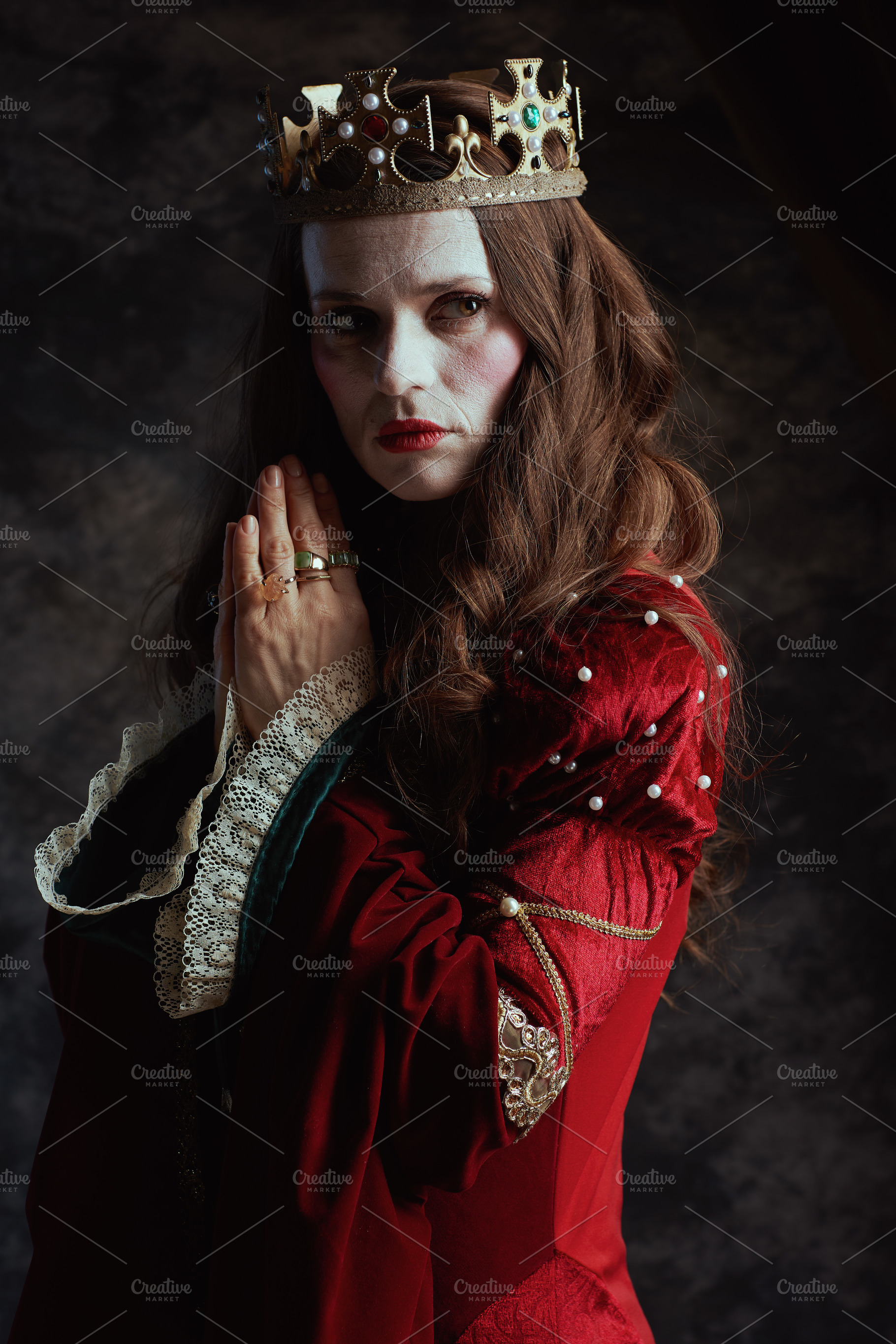 pensive medieval queen in red dress with crown praying, a Person Photo by Alliance Images