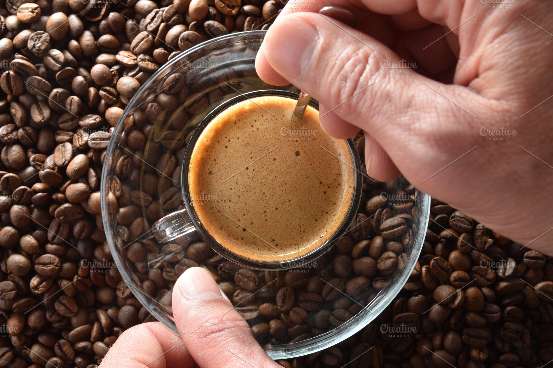 Hands stirring freshly brewed coffee over pile of coffee beans, a Food & Drink Photo by Davizro's Market