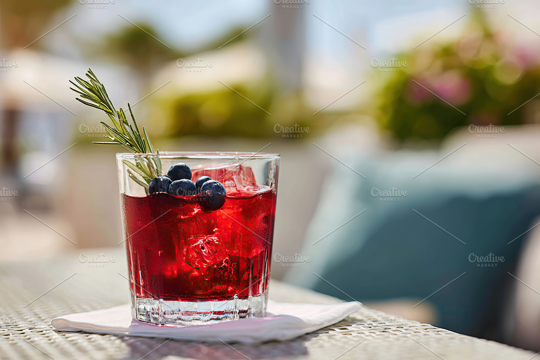 Refreshing cocktail with blueberries and rosemary on a sunny outdoor patio, a Food & Drink Photo by AlyaAnd