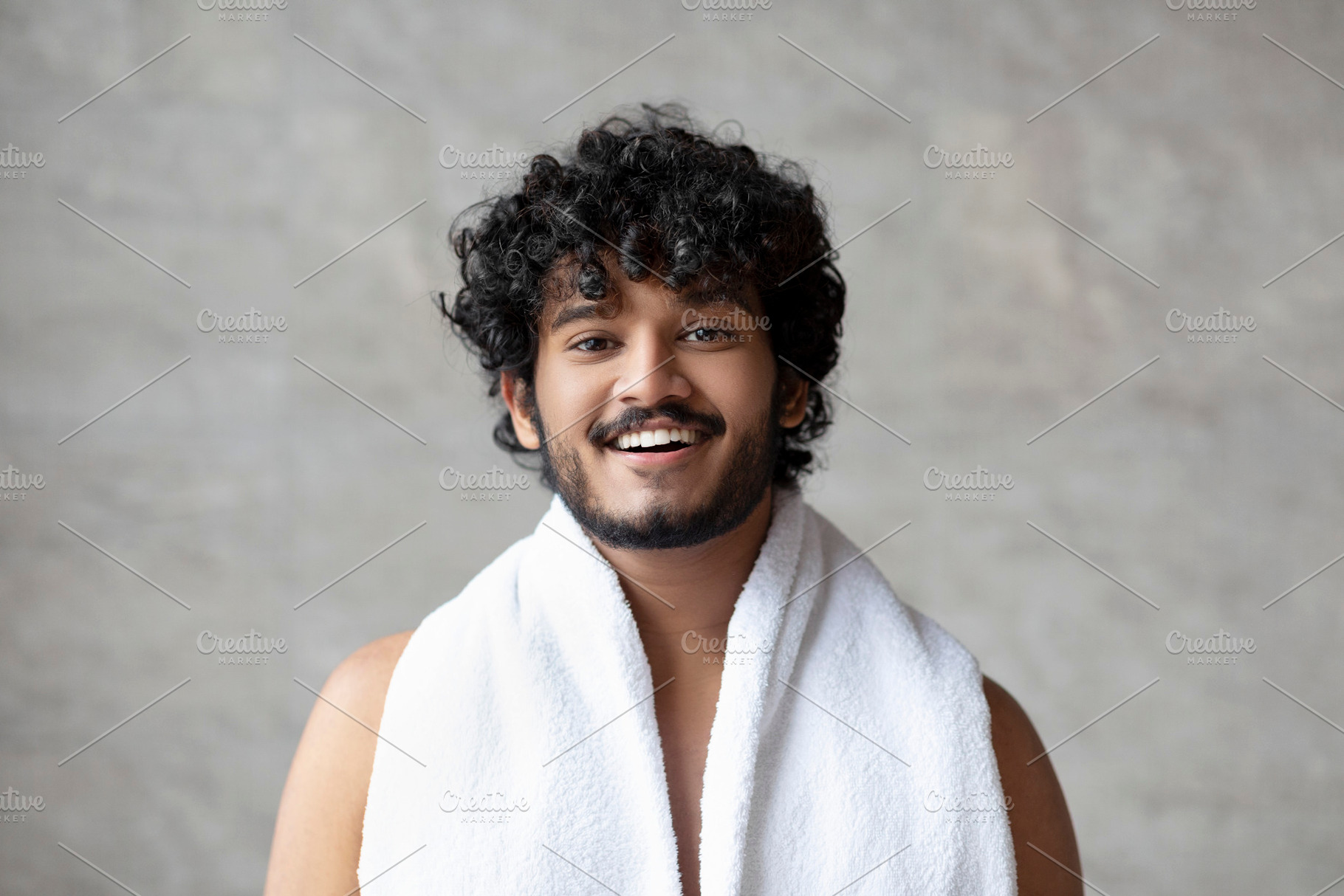 Excited bearded indian guy with towel on shoulders posing in bathroom and smili, a Person Photo by Prostock-Studio