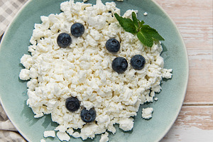 Cottage cheese with blueberries and mint on rustic table, a Food & Drink Photo by Olena Rudo
