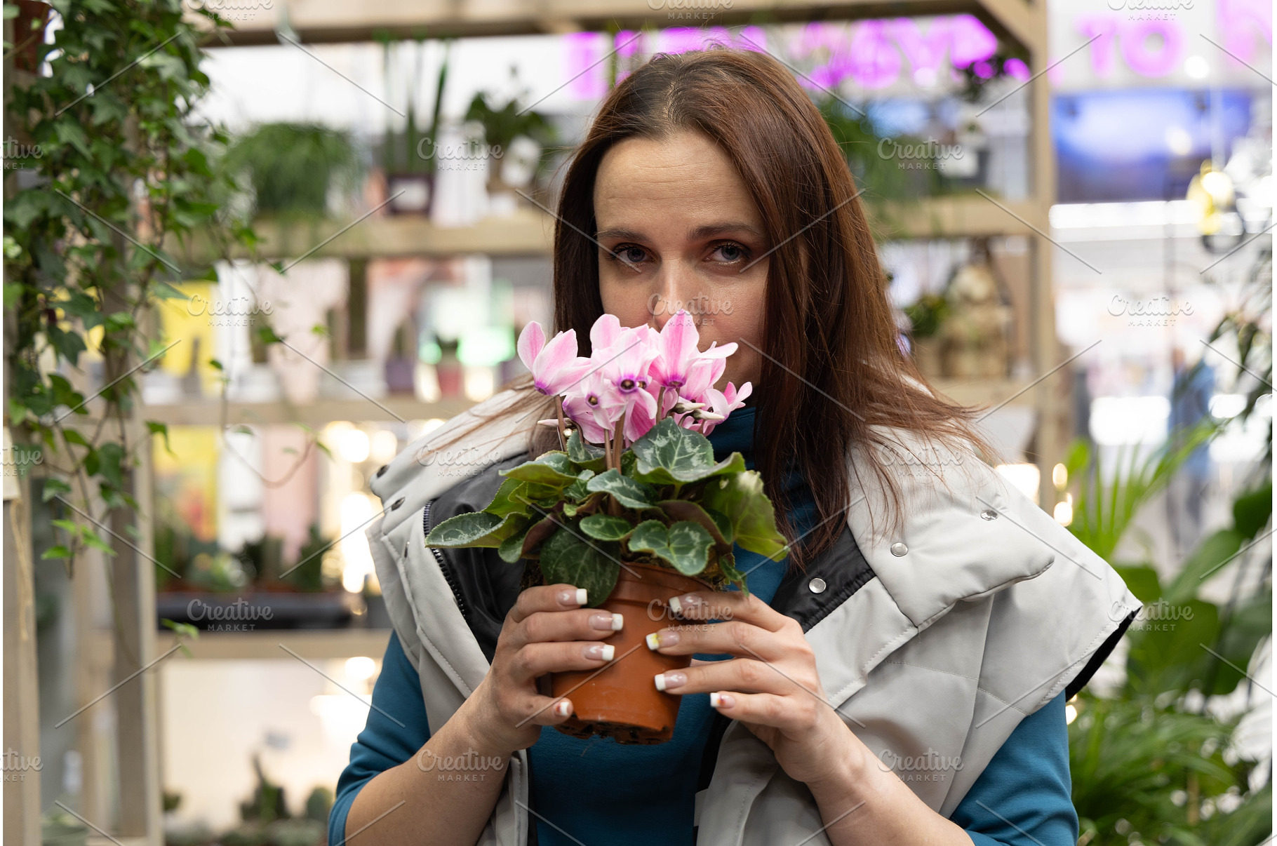 Woman in a florist smelling a flower, a Person Photo by Nenahliadava Design