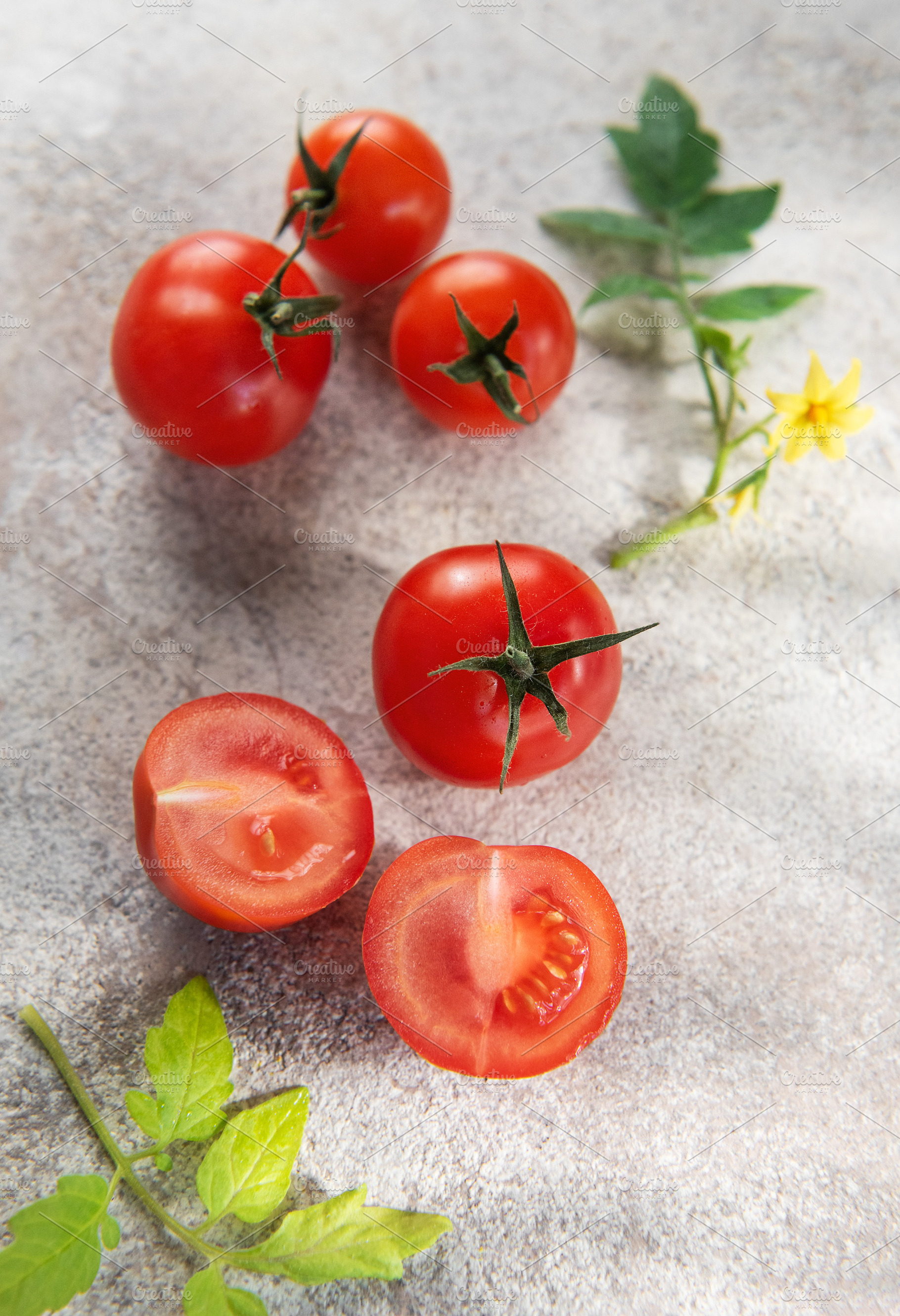 Fresh red cherry tomatoes on concrete background with leaves, a Food & Drink Photo by Olena Rudo