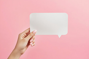 Hand holding a blank white speech bubble against a pink background in a creativ, a Background Photo by AlyaAnd
