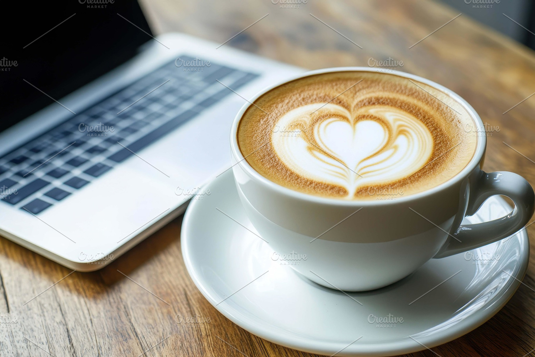 Coffee with latte art beside a lapto, a Photo by Tanuart