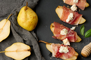 A slice of pear wrapped in prosciutto, topped with cheese and se, a Food & Drink Photo by ndanko