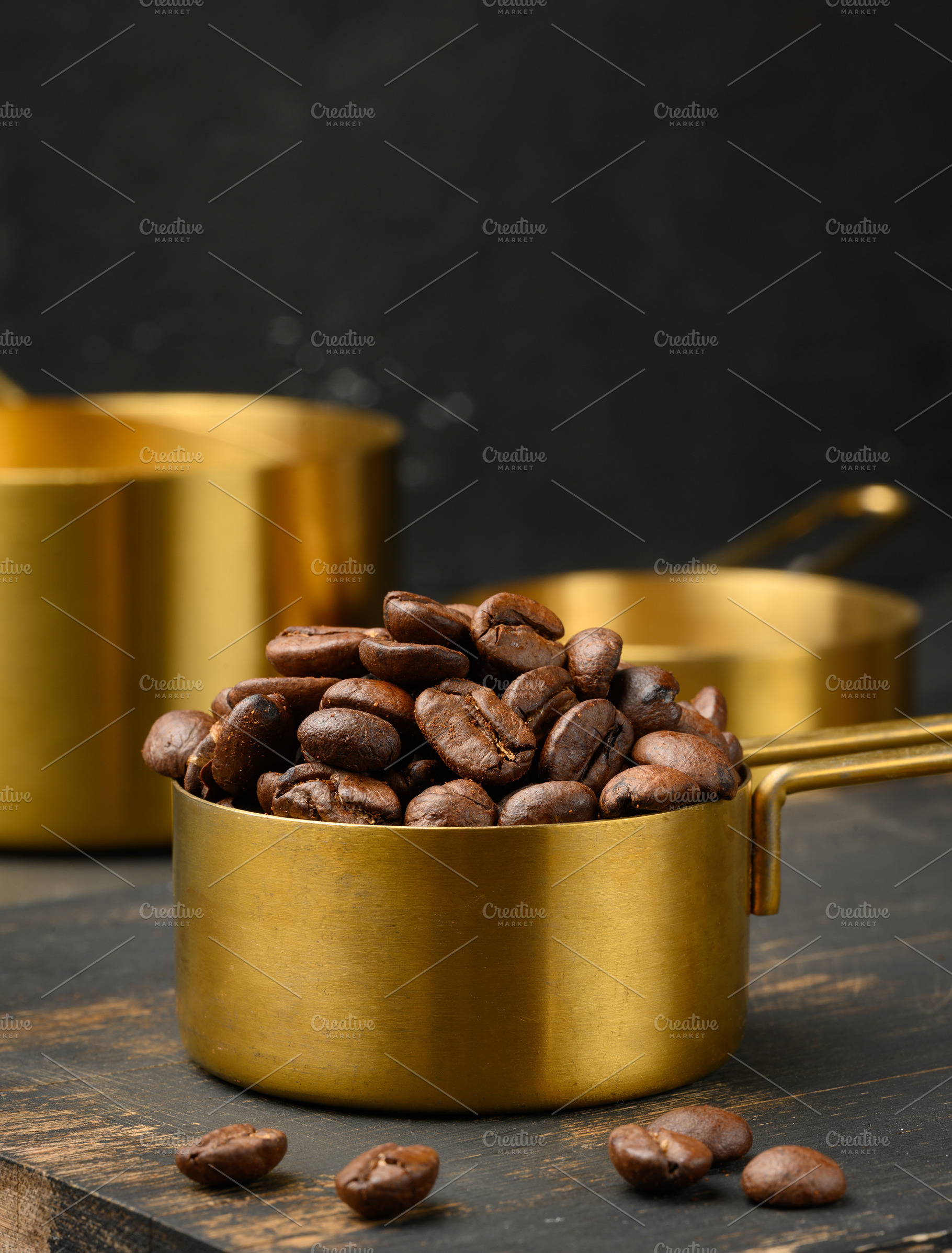 Roasted coffee beans are heaped into a golden metal measuring cu, a Food & Drink Photo by ndanko