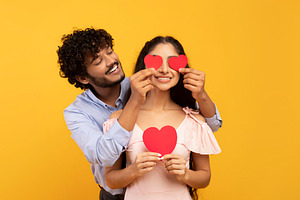 Affection. Loving indian husband covering wife's eyes with paper hearts, posing, a Person Photo by Prostock-Studio