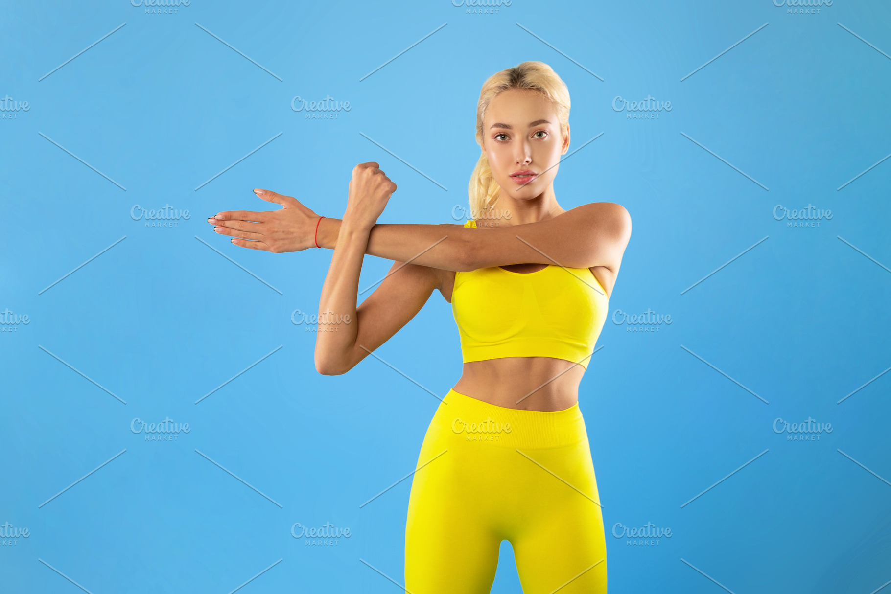 Portrait of confident young slim woman stretching her arms, a Photo by Prostock-Studio