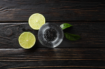 Glass of water, lime and leaves on wooden background, a Food & Drink Photo by AtlasStudio PRO
