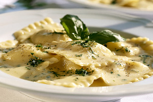 Ravioli pasta served in a creamy sauce with fresh basil and herbs, italian trad, a Photo by Studio ANNA
