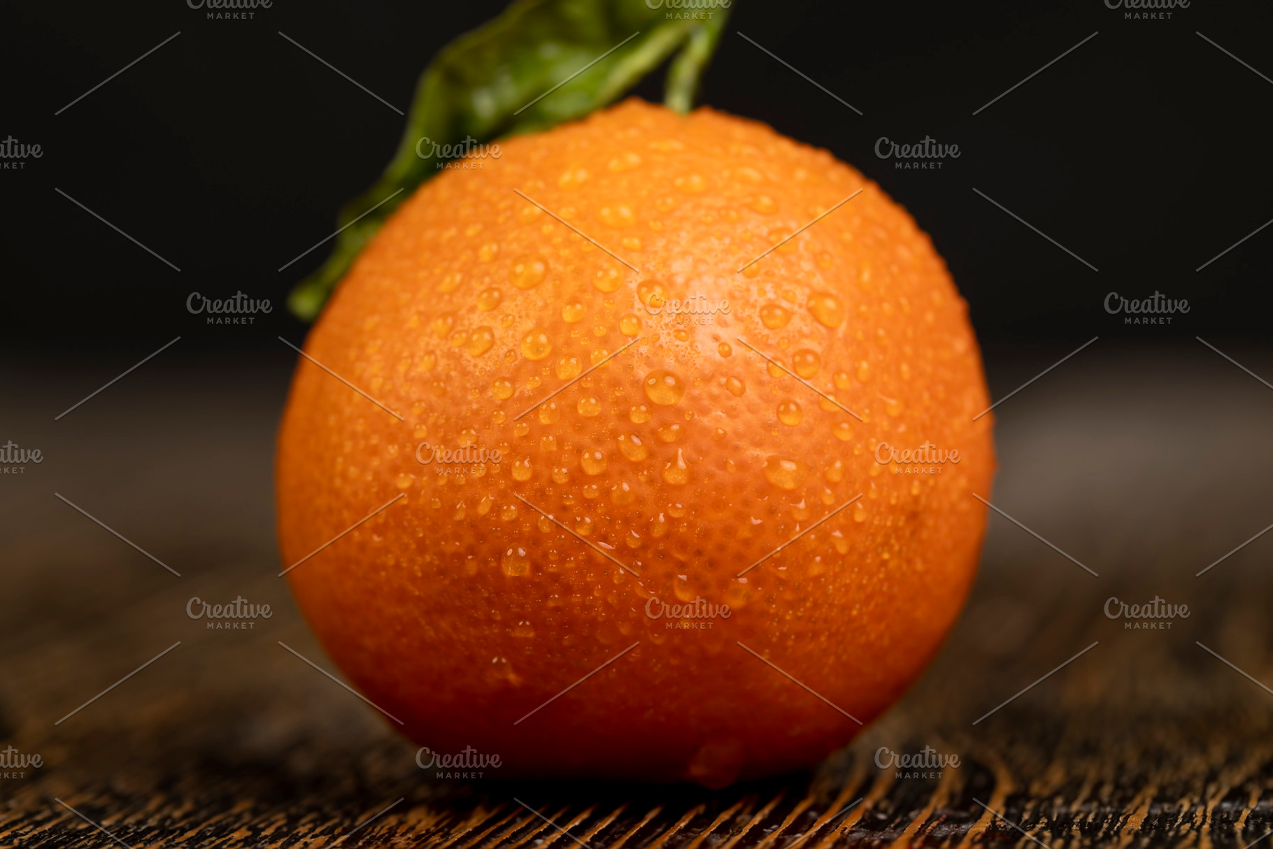 one tangerine with a dried green leaf covered with drops of water, a wet ripe o, a Photo by rsoollAI