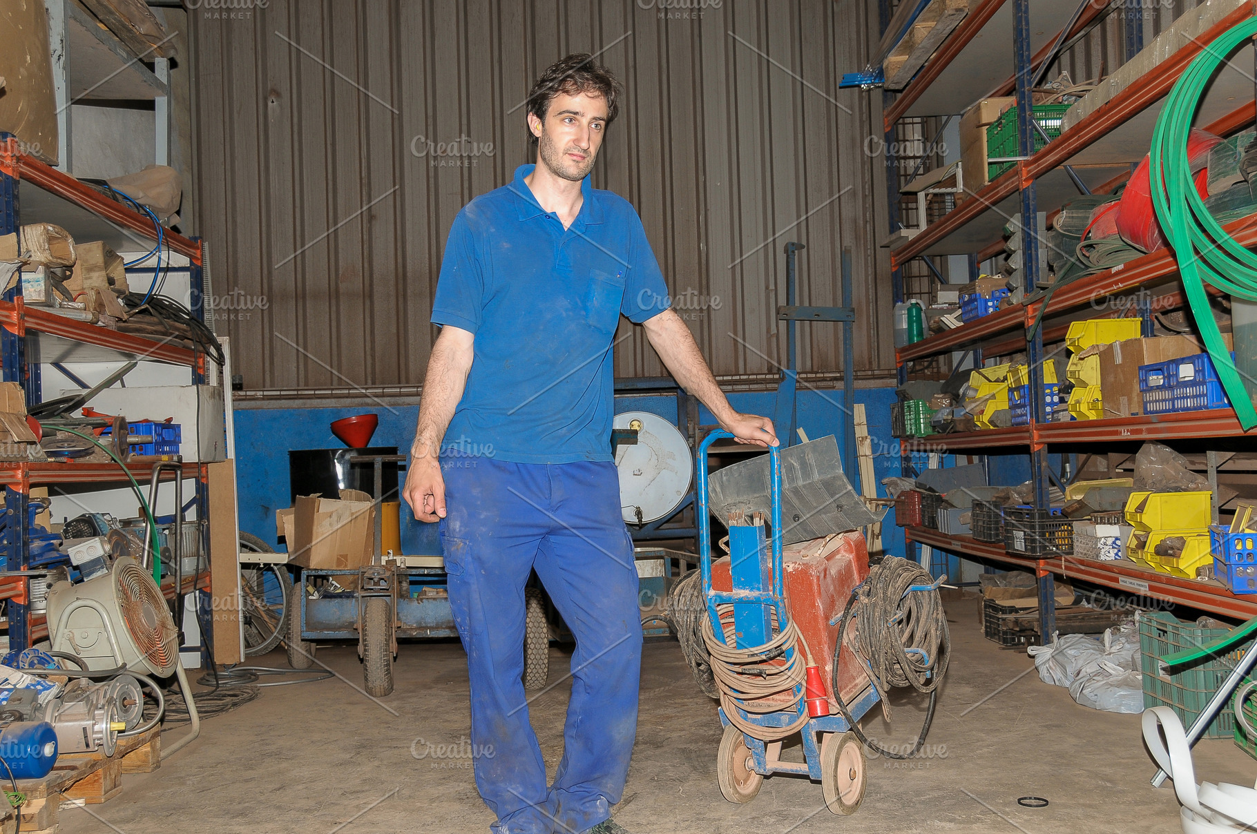Factory worker moving equipment cart in warehouse, an Industrial Photo by Davizro's Market