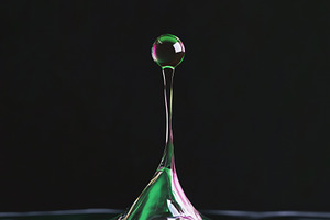 A close-up of a water droplet creating a splash, with vibrant green and purple, a Photo by Textures & Backgrounds