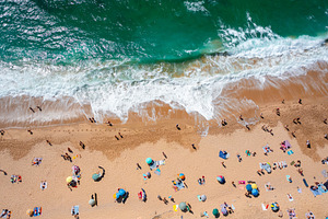 Overhead drone view of anonymous tourists and parasols on sandy shore, a Photo by andreonegin market