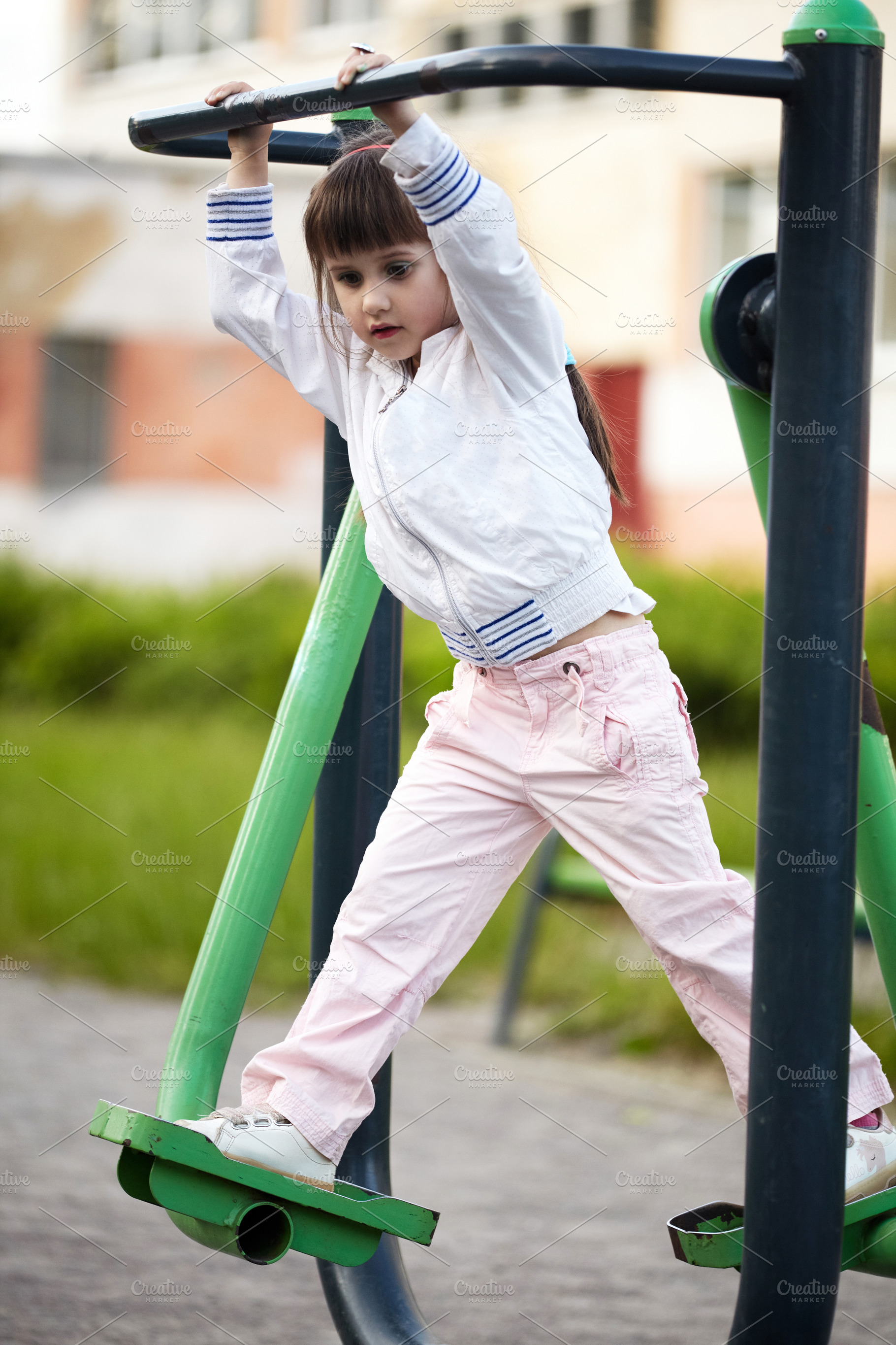 Little girl playing on an outdoor adult fitness machine at a public park., a Person Photo by Rohan Photography