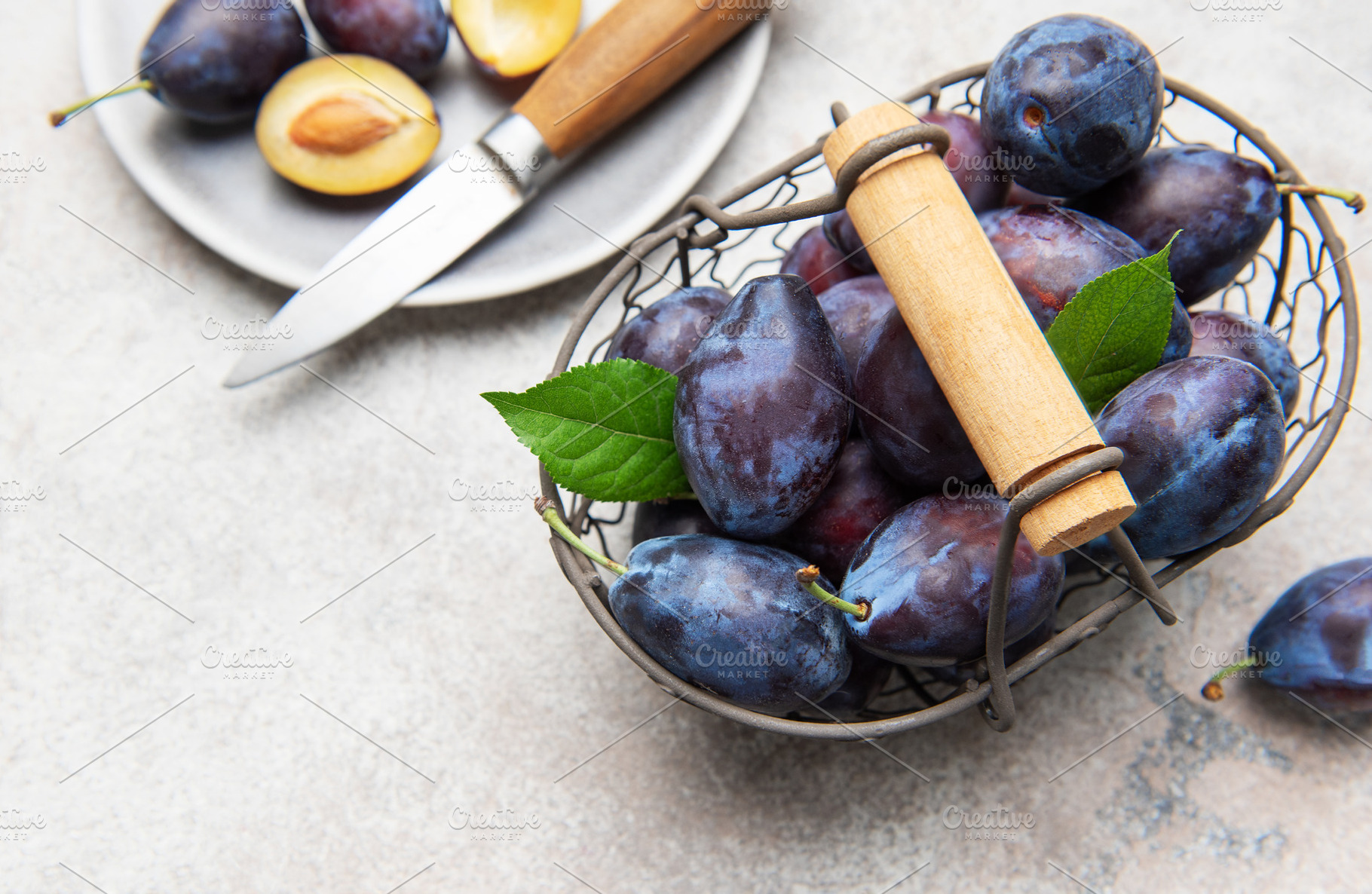 Fresh plums in basket with sliced fruit, a Food & Drink Photo by Olena Rudo