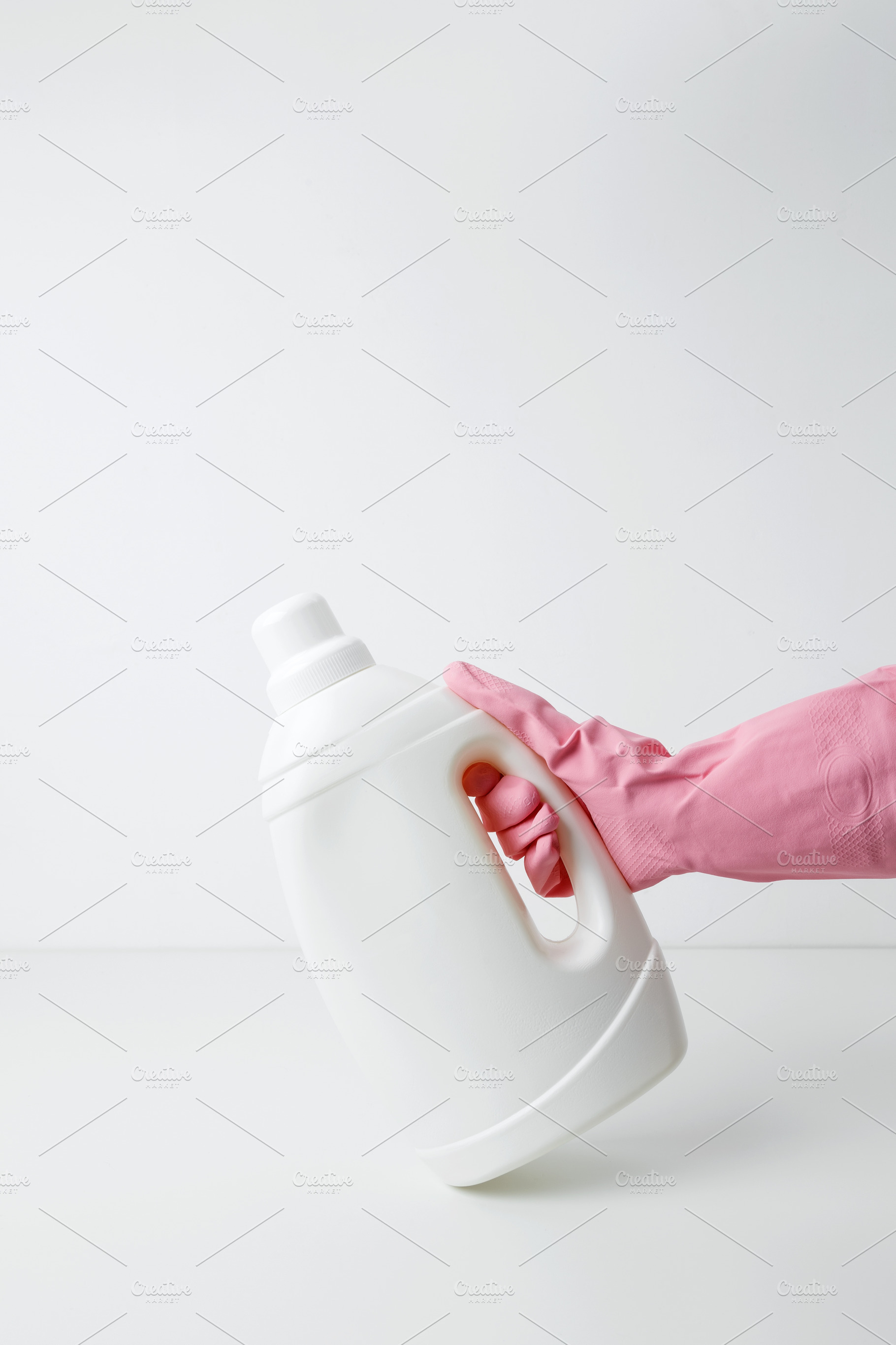 Female hand in a pink rubber glove holding a white branding mockup of laundry g, a Photo by matucha