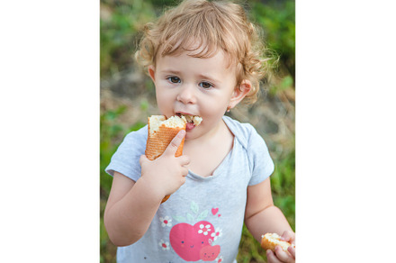 A child eats bread in the park, a Person Photo by yanadjana