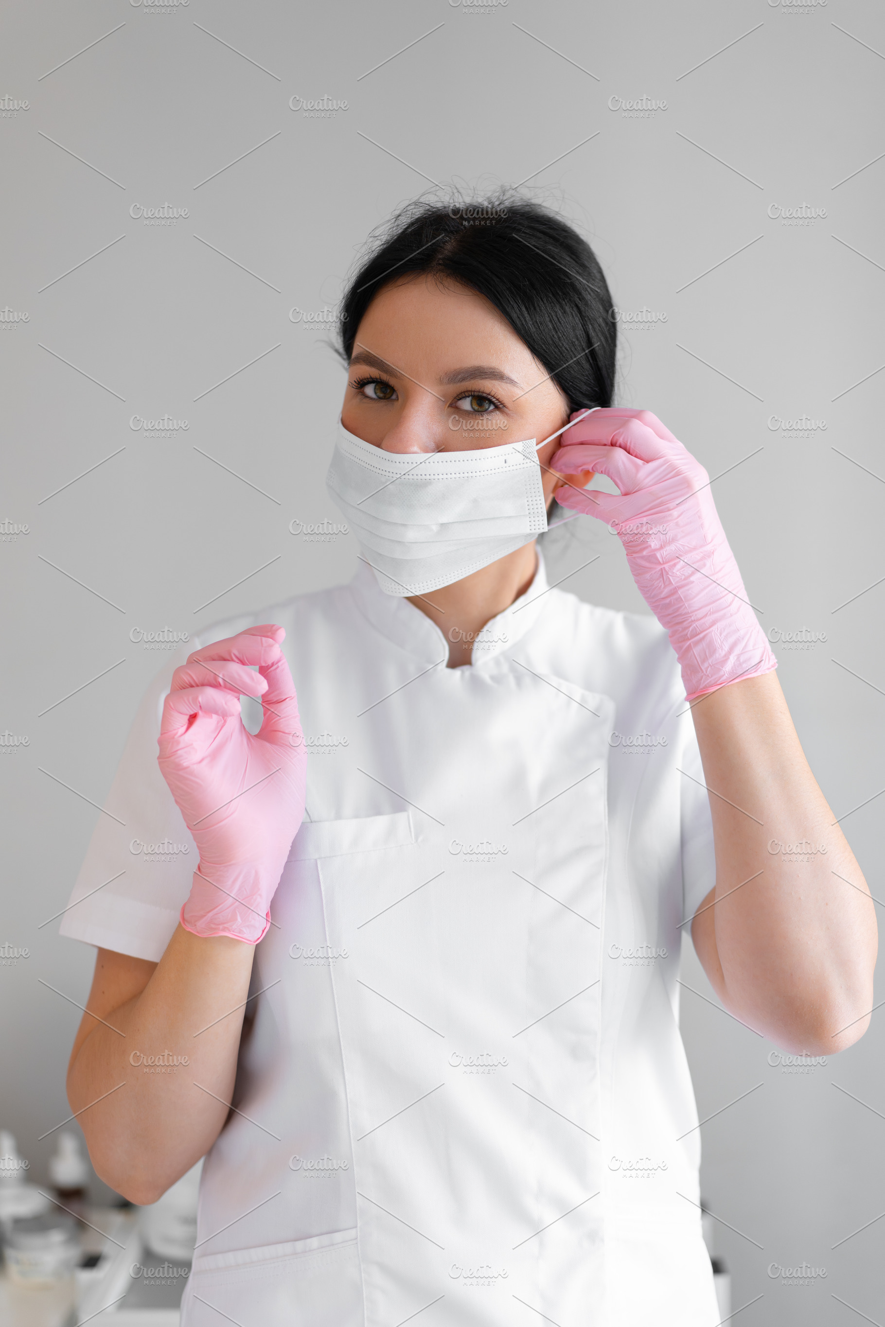 Female dermatologist wearing surgical mask and pink gloves in clinic, a Person Photo by andreonegin market