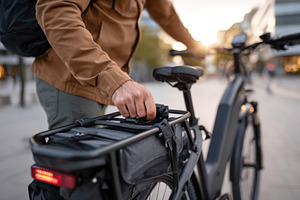Adjusting bag on electric bike in urban setting, a Transportation Photo by AlyaAnd
