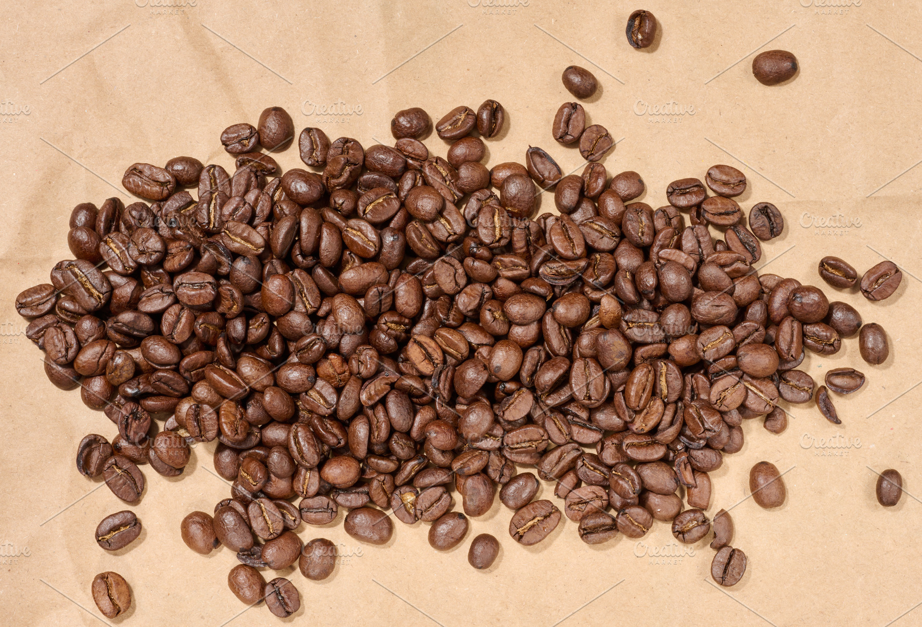 Scattered roasted coffee beans on brown paper, a Food & Drink Photo by ndanko