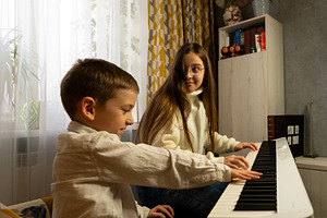Boy presses piano keys while girl, a School & Education Photo by Elena Vagengeim