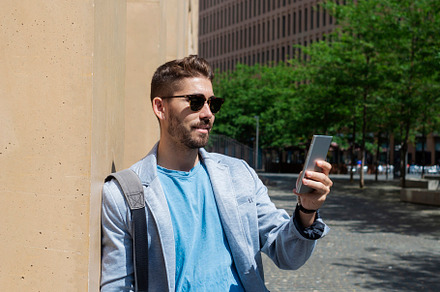 Handsome young man smiling when he is using his mobile phone, a Person Photo by RF Images