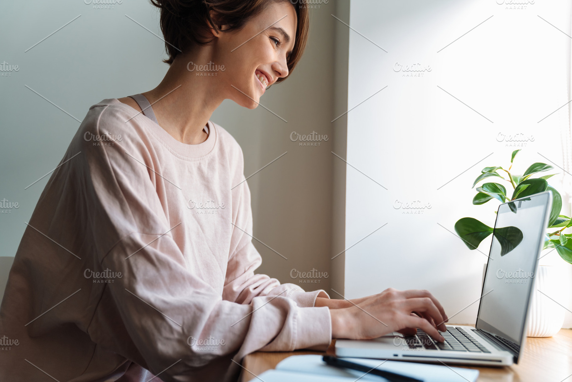 Happy beautiful girl smiling while working with laptop at window, a Person Photo by Dean Drobot